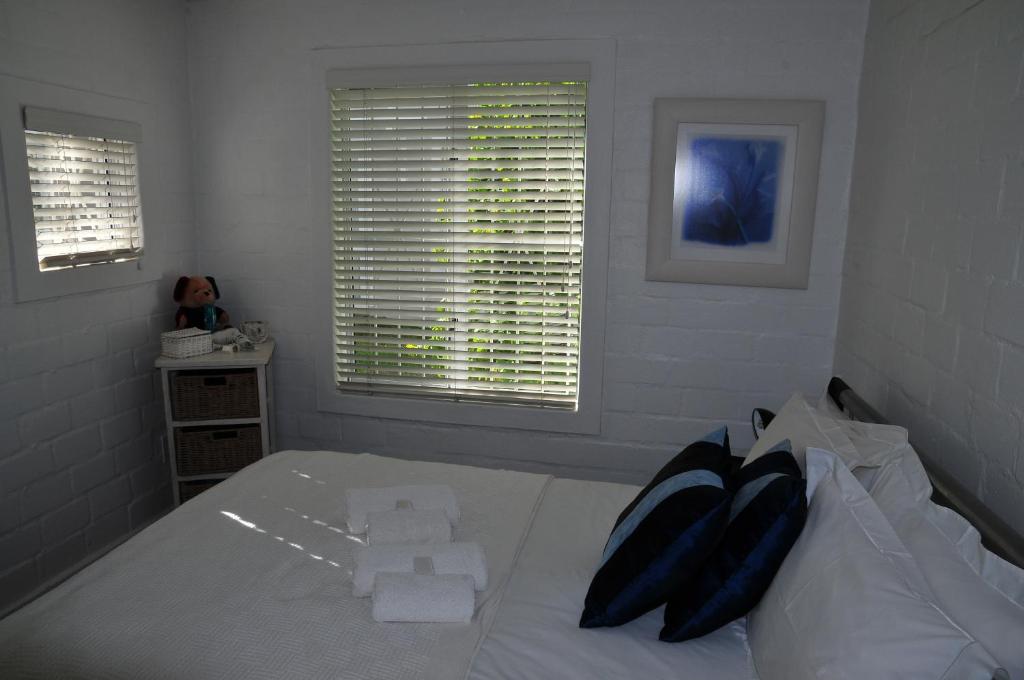 a bedroom with a white bed and two windows at Bradclin @ York in Cape Town