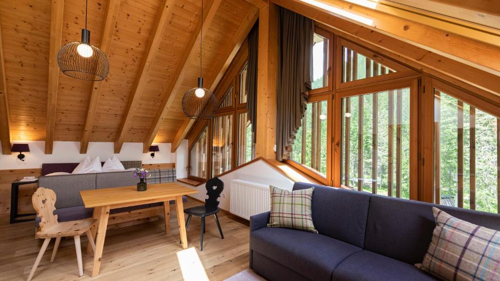 een woonkamer met een blauwe bank en een tafel bij Natura Boutique Chalet Wellness SPA in Dobbiaco