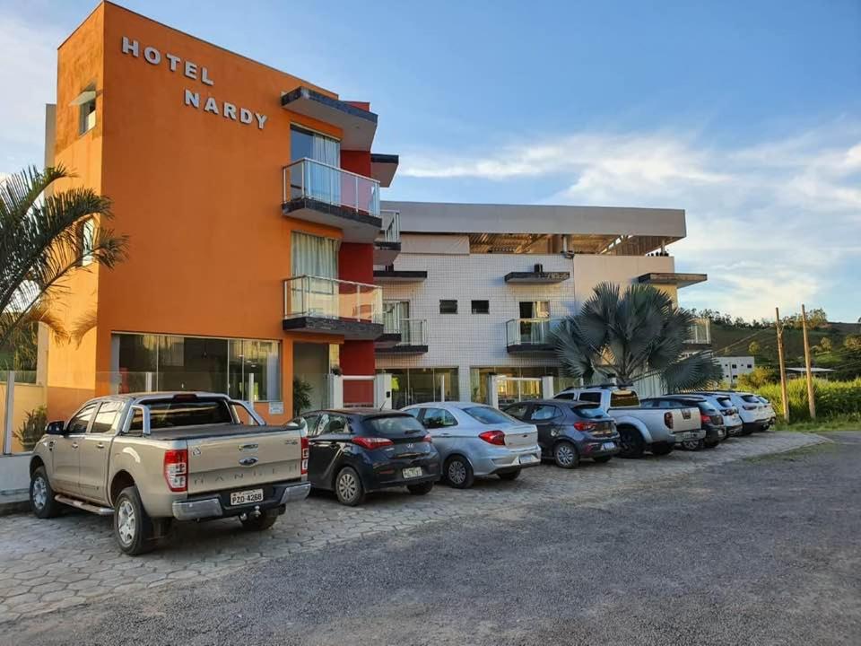 a hotel with cars parked in a parking lot at Hotel Nardy in Alvinópolis