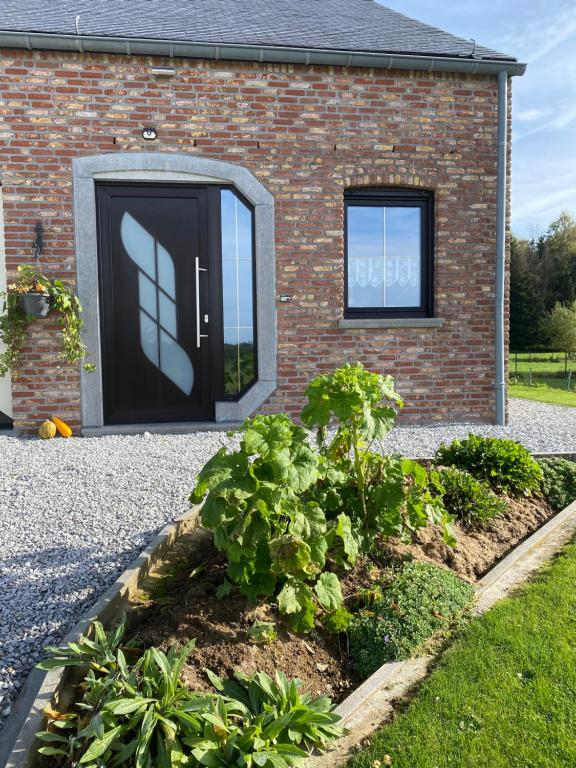 uma casa de tijolos com uma porta preta e um jardim em L'évasion du berger australien em Couvin