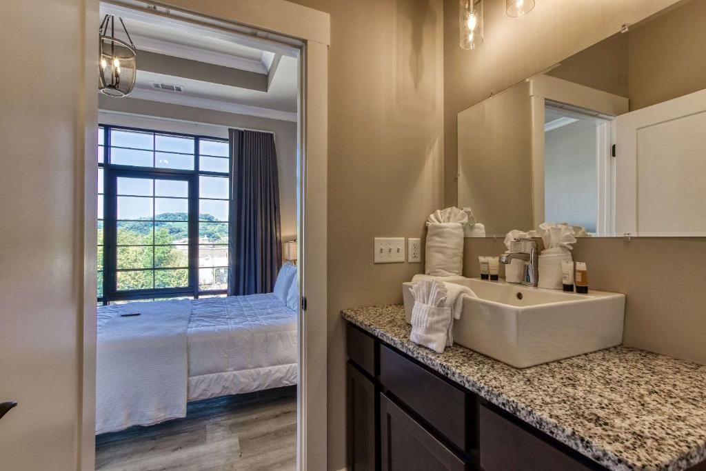 a bathroom with a sink and a bedroom at Central Hotel, Ascend Hotel Collection in Sevierville