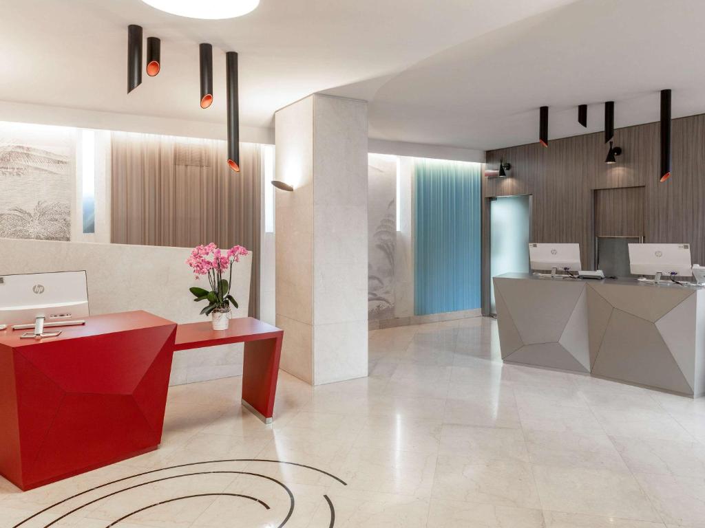 a lobby with a red desk with flowers on it at Mercure Roma Centro Colosseo in Rome