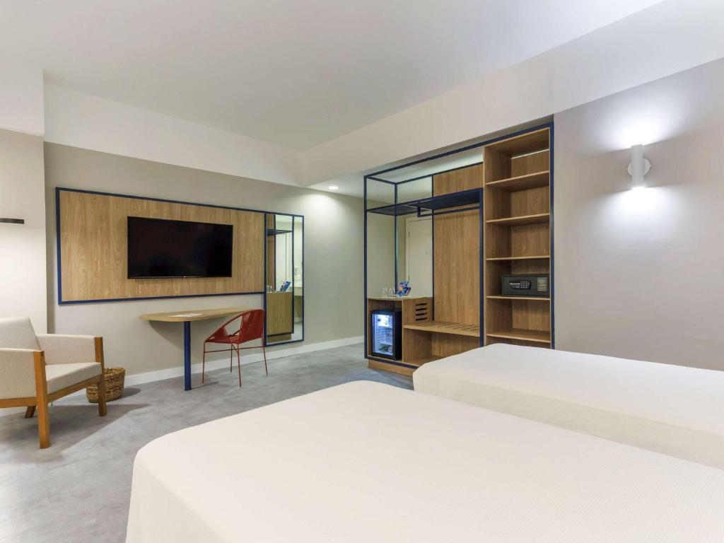 a living room with a large bed and a television at Novotel Salvador Rio Vermelho in Salvador