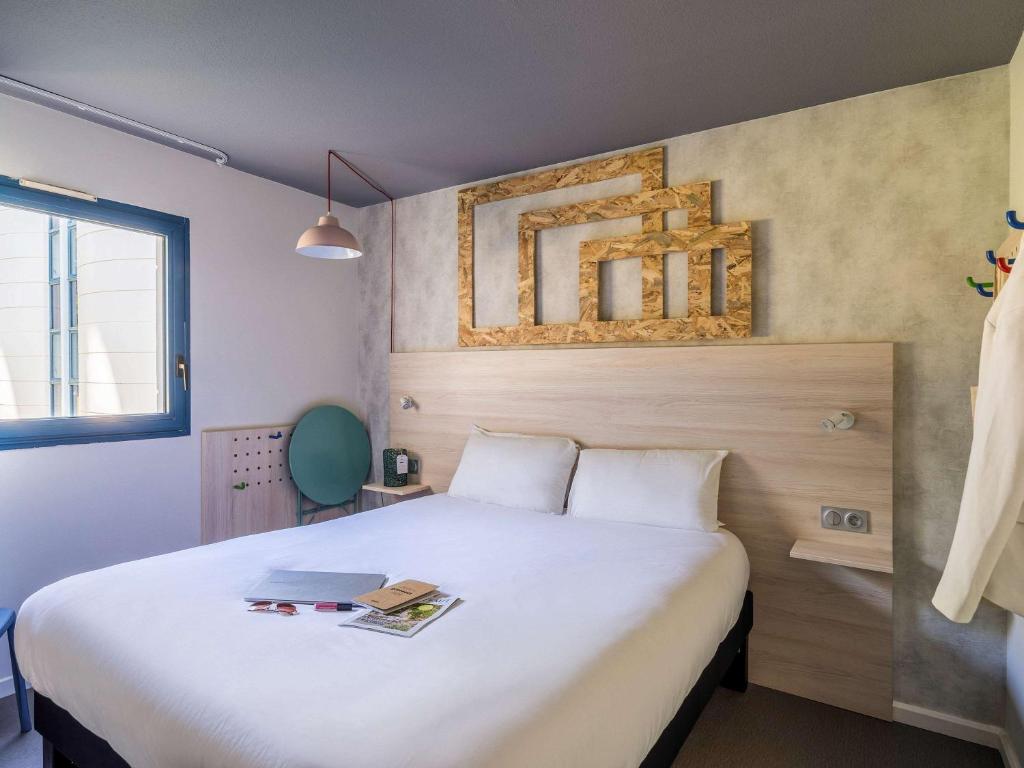 a bedroom with a large bed with a laptop on it at greet Hotel Bordeaux Aeroport in Mérignac