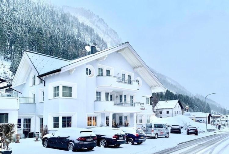 duży biały budynek z samochodami zaparkowanymi na śniegu w obiekcie Apart Laresch w mieście Ischgl