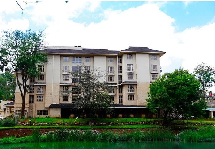 un gran edificio de apartamentos con árboles y un estanque en Qaribu Inn Boutique Hotel Nairobi en Nairobi