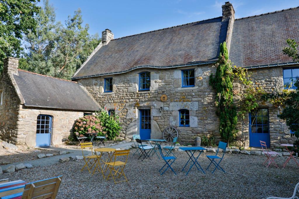 a stone house with chairs and a table in front of it at Des Feuilles et Des Hiboux in Plescop