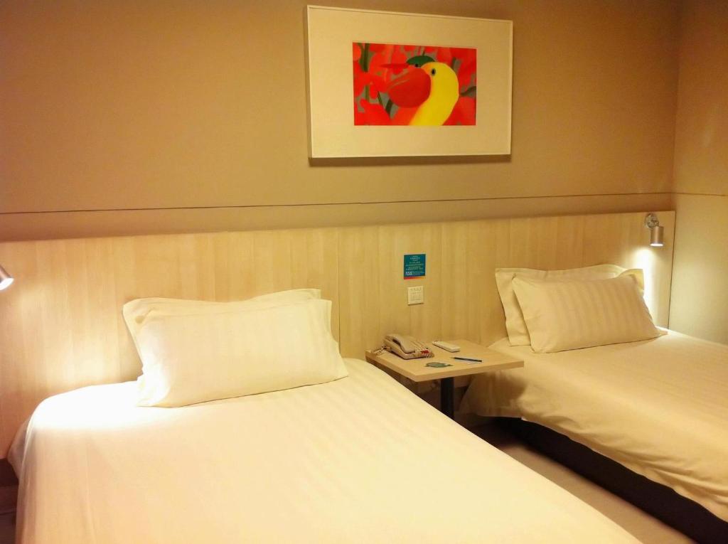 a hotel room with two beds and a picture on the wall at Jinjiang Inn - Wuxi Wangzhuang Road in Wuxi