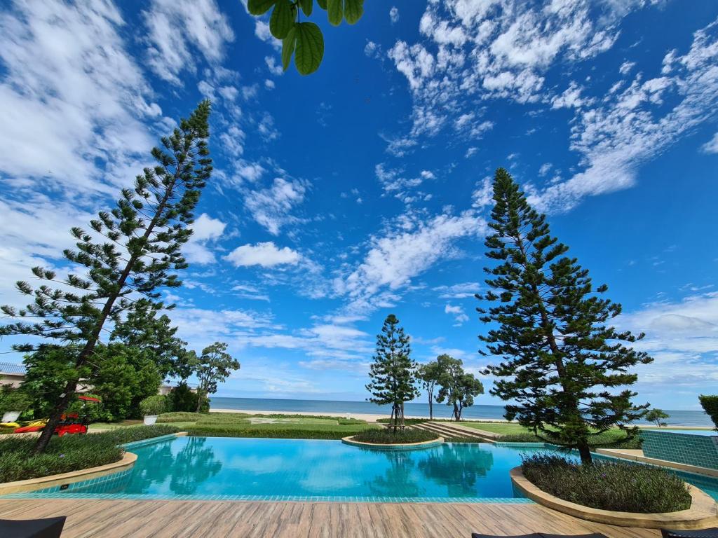 una piscina con árboles y el océano en el fondo en AMARA Pool Villa at Boulevard Tuscany Cha Am - Hua Hin, en Cha Am