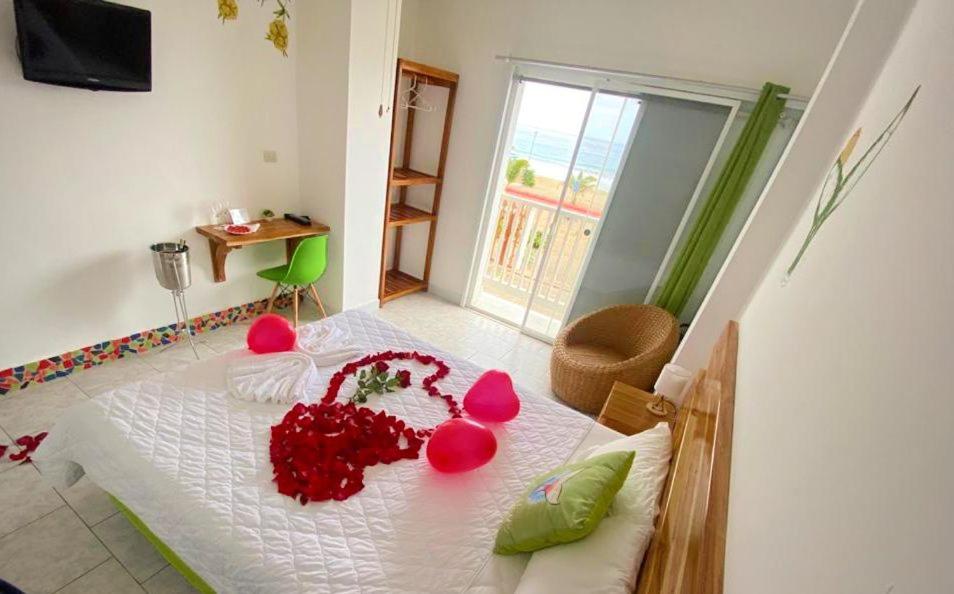 Una habitación con una cama con flores rojas. en Whale House Hotel, en Puerto López