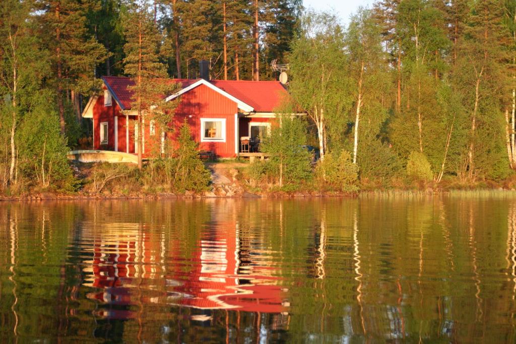 una casa roja en la orilla de un cuerpo de agua en Holiday house in Gnosjo with amazing lake view, en Gnosjö