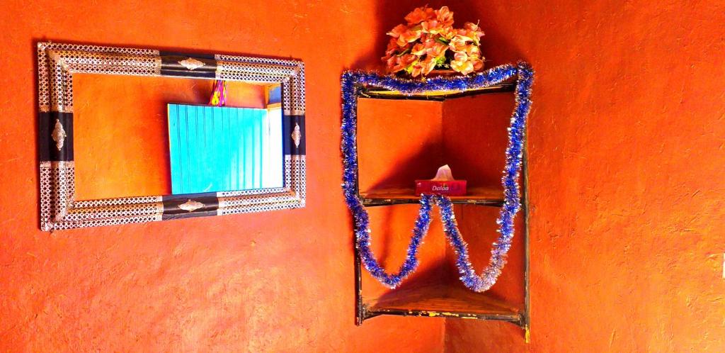 a mirror hanging on a wall with a candle at Auberge Camping Ocean des dunes in Merzouga