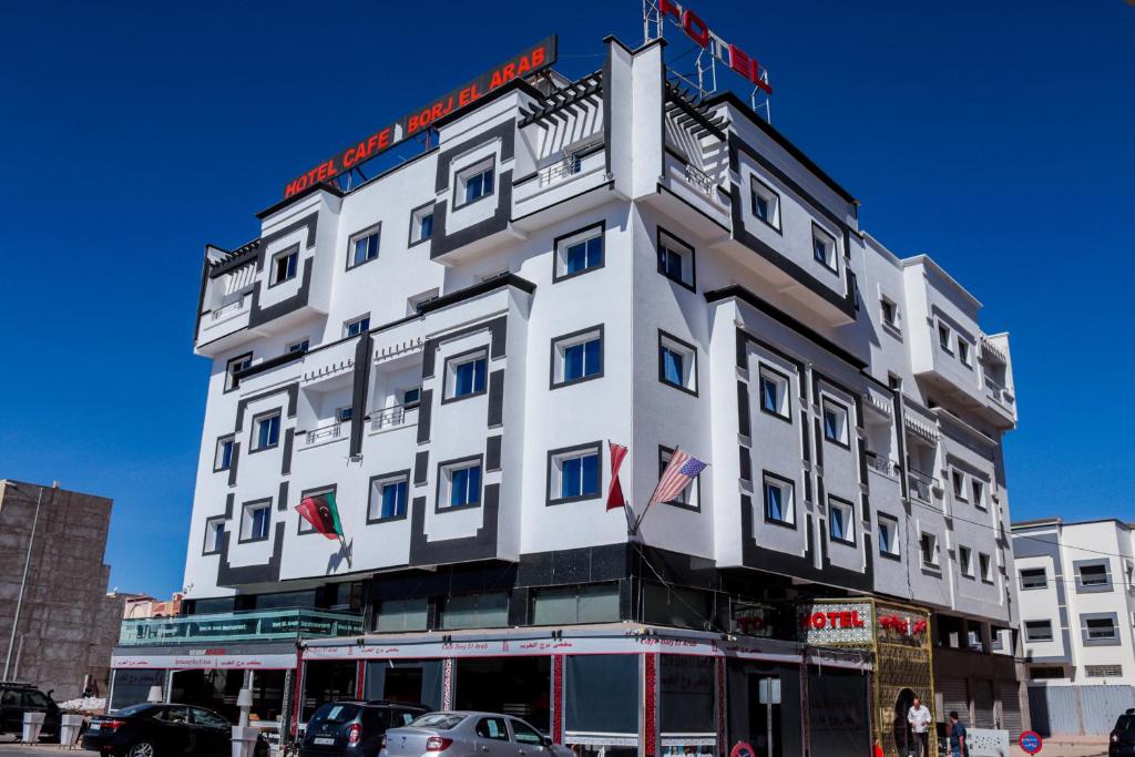 un gran edificio blanco con banderas. en HOTEL BORJ EL ARAB en Khouribga
