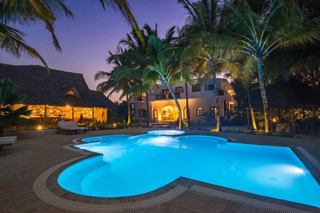 a swimming pool in front of a house with palm trees at Amani Boutique Hotel - Small Luxury Hotels of the World in Paje