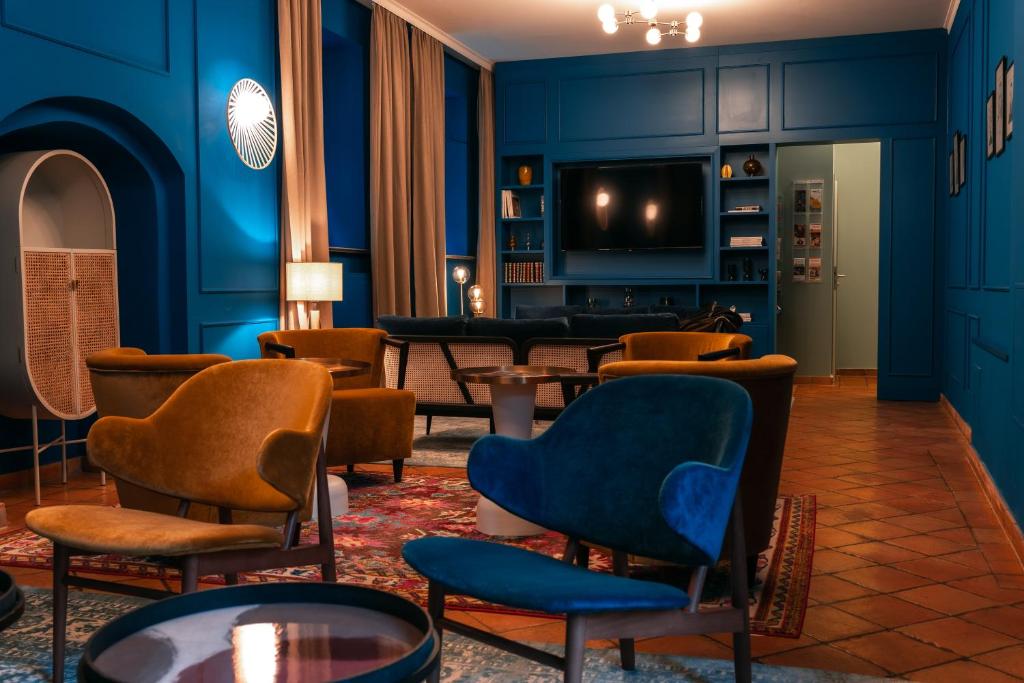 a living room with blue walls and chairs and a tv at Hotel Erbenhof in Weimar