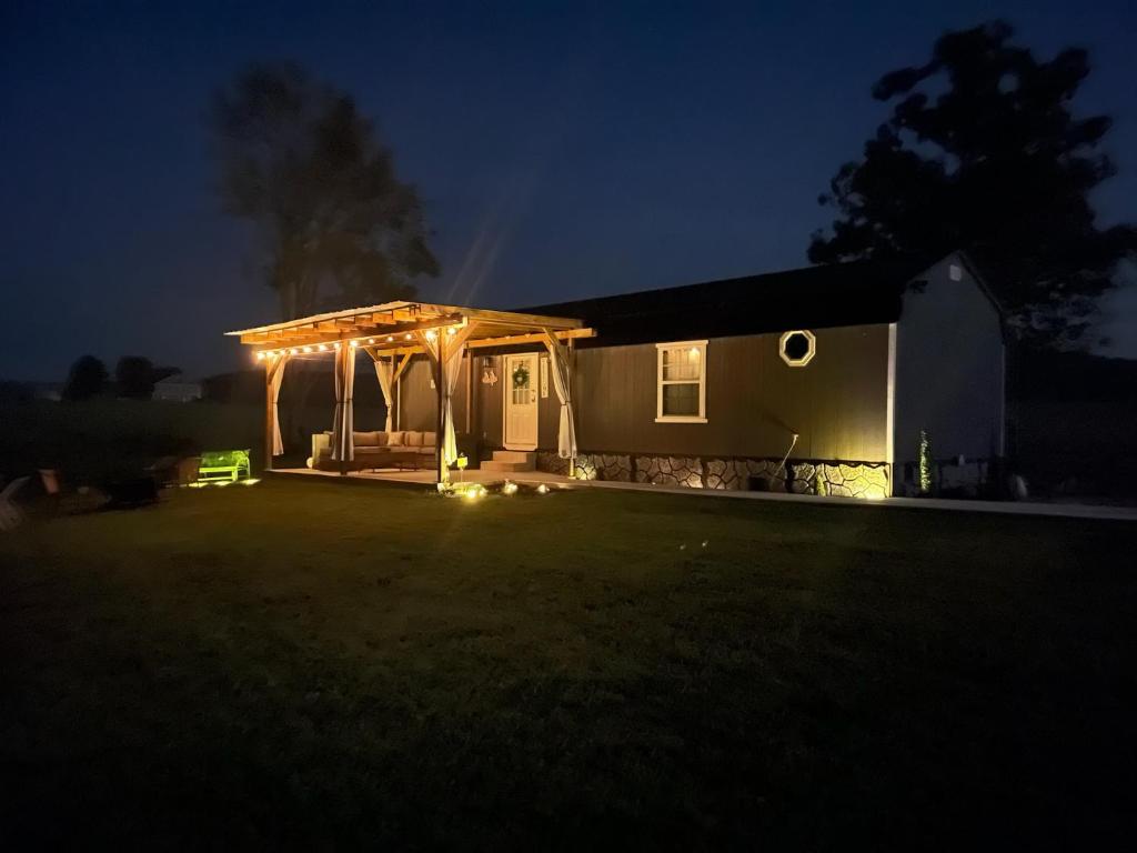 ein nachts beleuchtetes Haus mit einer Pergola in der Unterkunft Little House by the Pond in Oneida