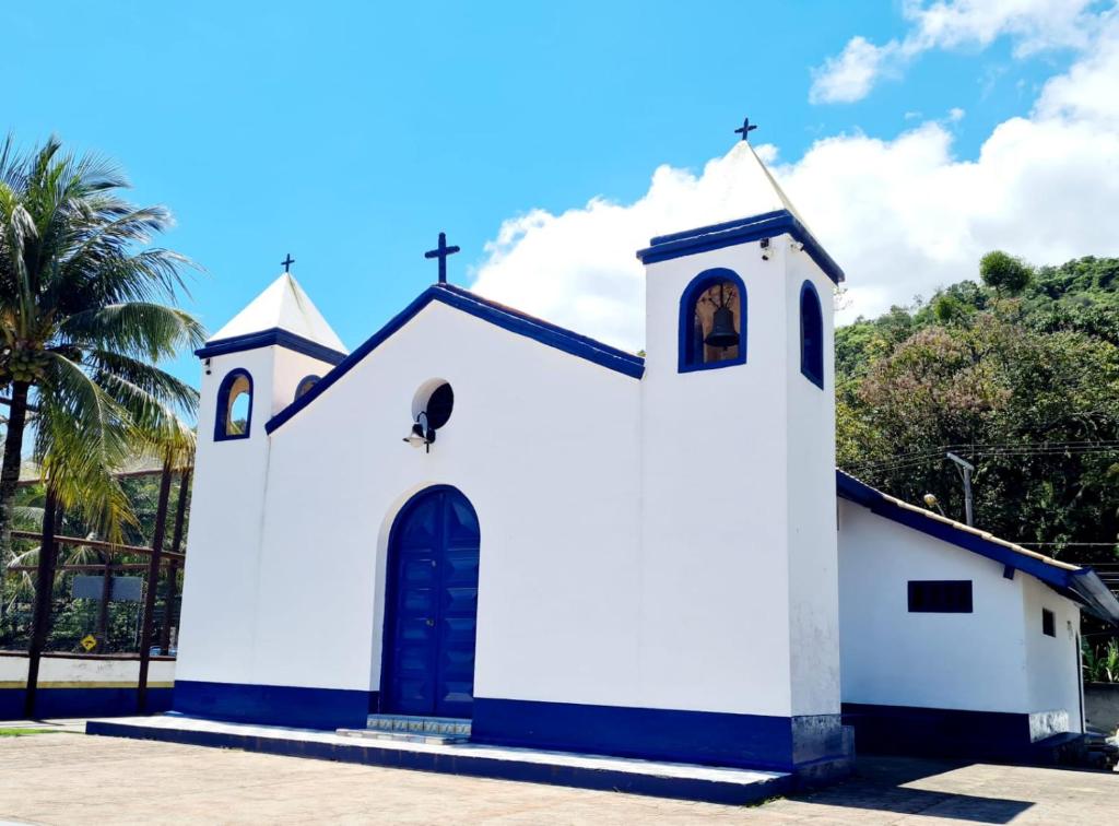 a small white church with a cross at Pousada Por do Sol in Ilhabela