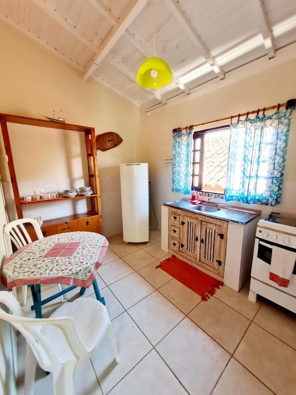 a kitchen with a table and a refrigerator at Pousada Por do Sol in Ilhabela