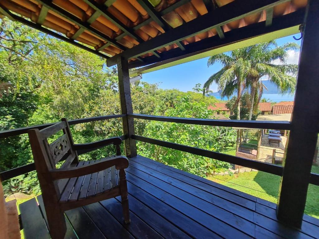 a porch with a bench and a palm tree at Pousada Por do Sol in Ilhabela