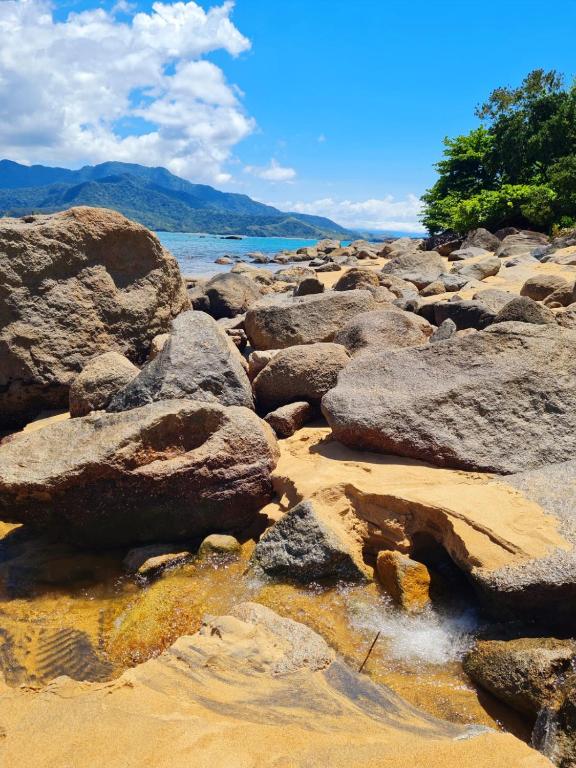 a group of rocks on a beach near the water at Pousada Por do Sol in Ilhabela