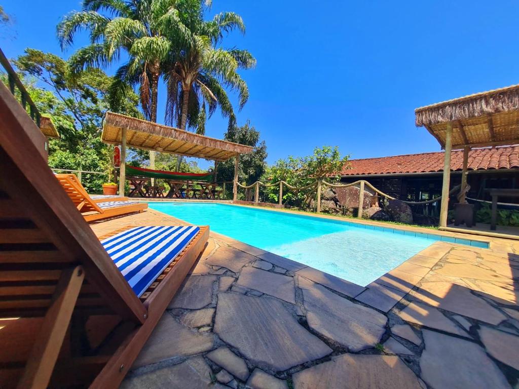 a swimming pool with a deck and chairs next to a house at Pousada Por do Sol in Ilhabela