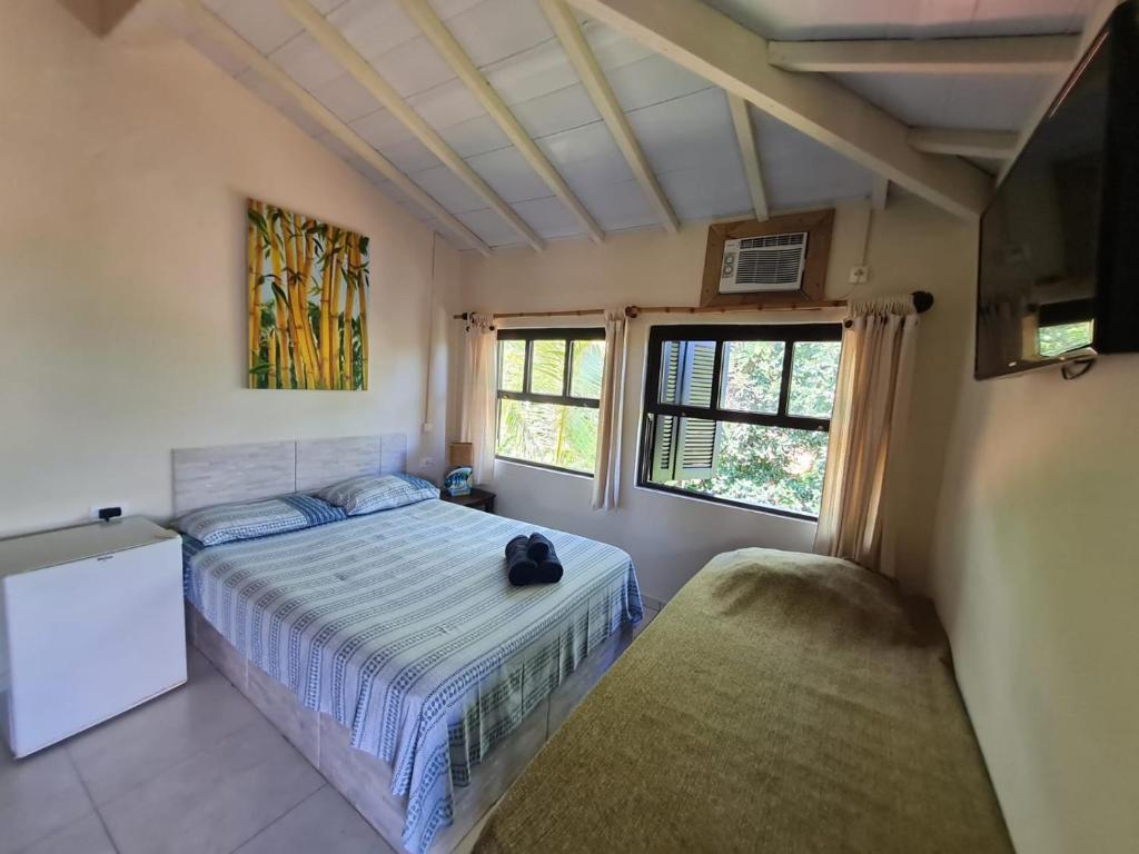 a bedroom with a bed and two windows at Pousada Por do Sol in Ilhabela