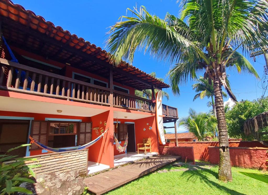 a house with a palm tree in front of it at Pousada Por do Sol in Ilhabela