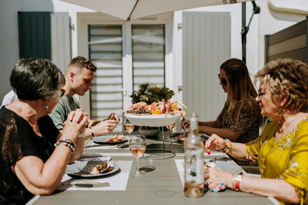 Eine Gruppe von Menschen, die an einem Tisch sitzen und Essen essen. in der Unterkunft L'annexe in La Cotinière