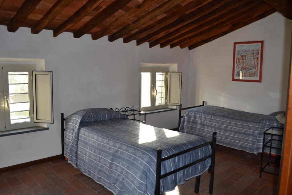 a bedroom with two beds and two windows at Corte Prata in Capannori