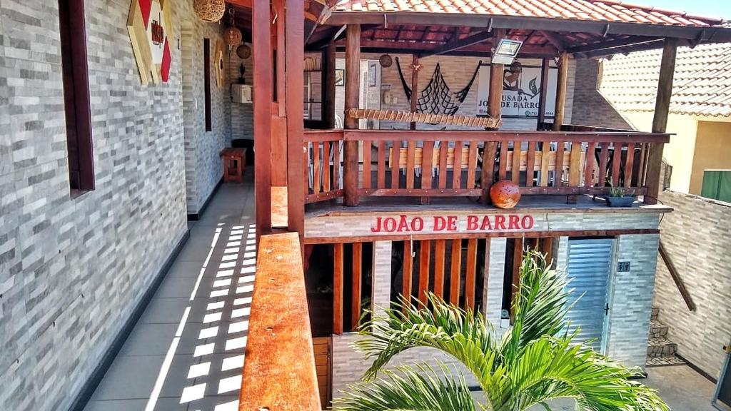 una terrazza in legno con un cartello sul lato di un edificio di Pousada João de Barro a Camaçari