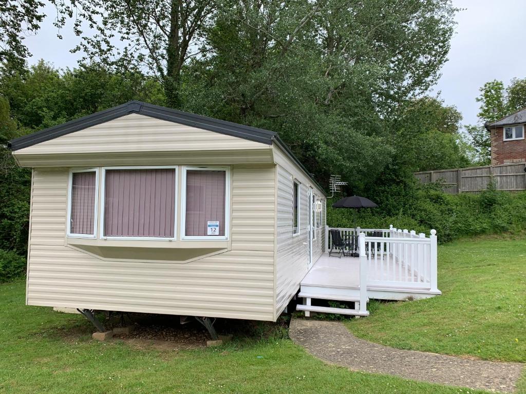 une petite maison dans une cour avec une terrasse couverte dans l'établissement Lower Hyde Caravan, à Shanklin