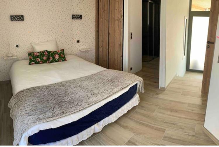 1 dormitorio con 1 cama y suelo de madera en Chambre avec salle de bains privative, en Hermonville
