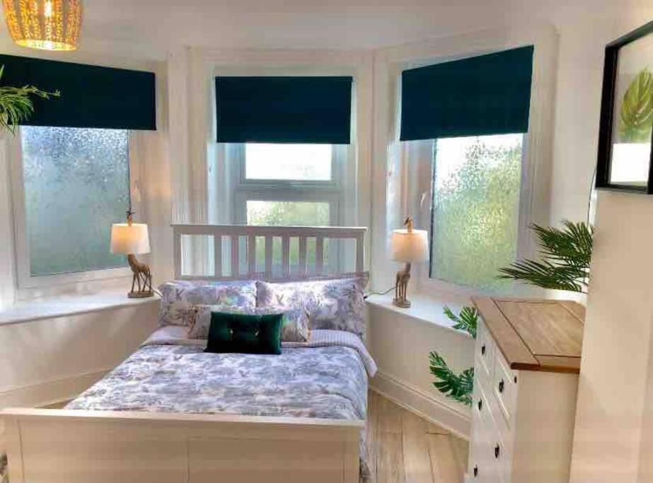 a bedroom with a bench in front of two windows at Casuarina in Ventnor