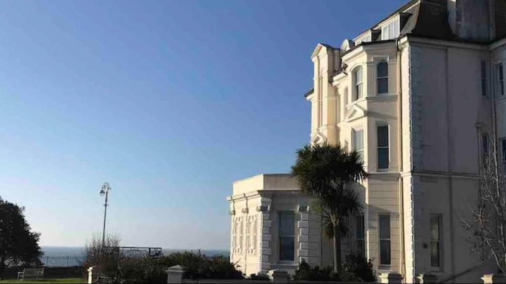 a white building with a palm tree in front of it at The Leas View in Folkestone