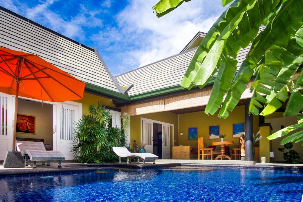 a house with a swimming pool next to a house with an orange umbrella at Villa Topaz in Laem Set Beach