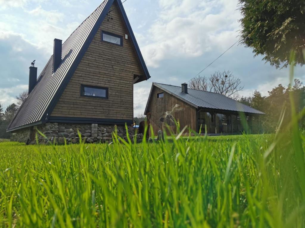 une maison au milieu d'un champ d'herbe dans l'établissement Na Zakręcie - Domek Wiejski, à Błędowo