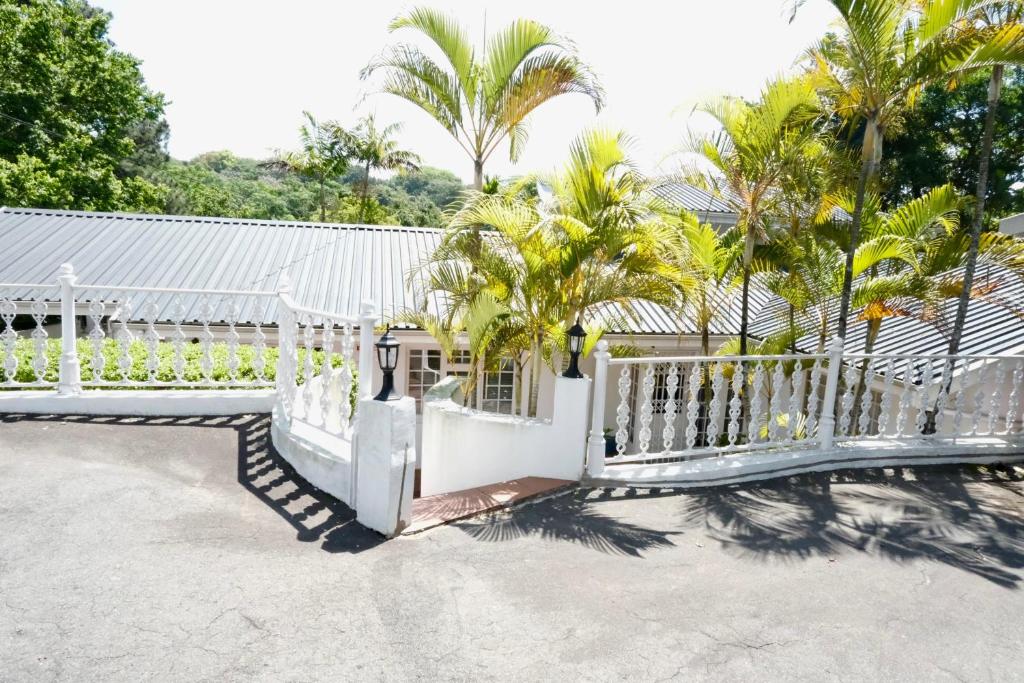 a white fence with palm trees in the background at The Whitehouse Bed and Breakfast in Durban