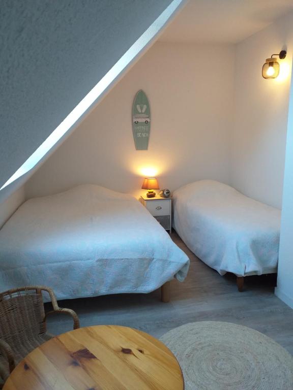 Habitación con 2 camas y mesa de madera. en Maison, 2 chambres, 400m de la plage., en La Turballe