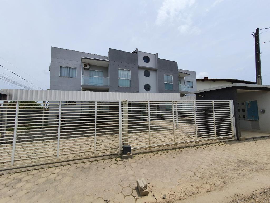a house behind a fence in front of a building at Apto Solar da Praia in Piçarras