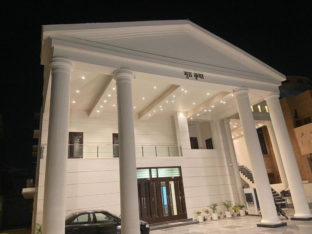 焦特布爾的住宿－Guru Kripa House，前面有柱子和汽车的大型白色建筑