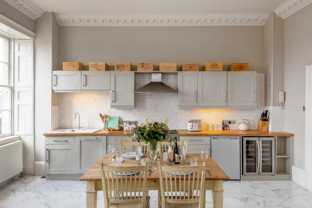 una cocina con armarios blancos y una mesa de madera con sillas. en Luxury Georgian Duplex in Central Bath, en Bath