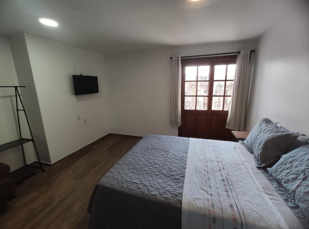 a bedroom with a bed and a television and a window at Bahia Pelô Hostel in Salvador