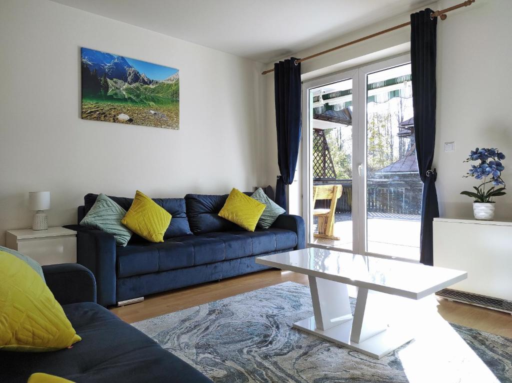 a living room with a blue couch and a table at Apartamentylove - Apartament Oliwia in Zakopane