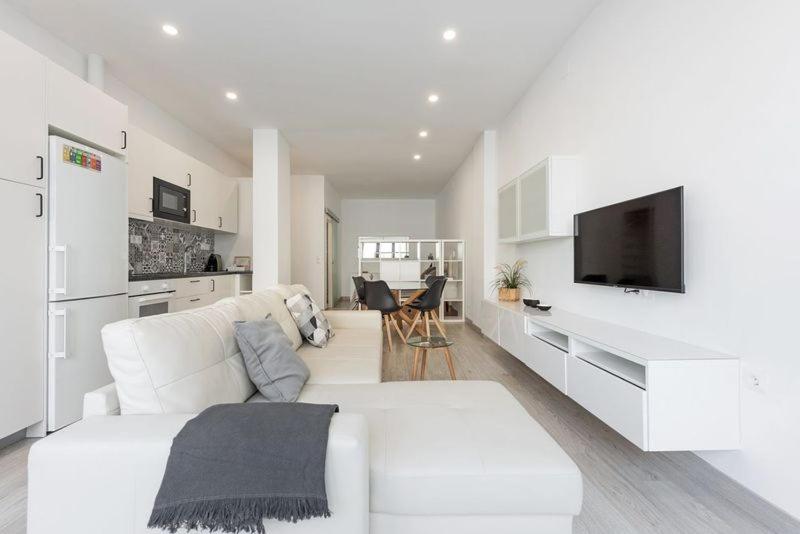 a white living room with a white couch and a tv at Charming loft B in Málaga