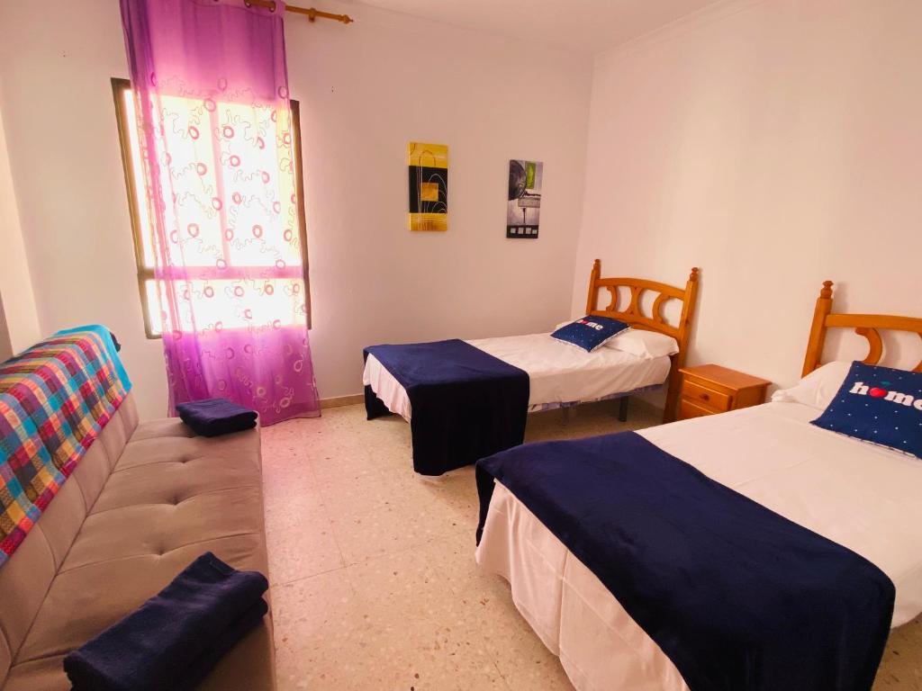 a bedroom with two beds and a couch and a window at SaVoa 869 in Gran Tarajal