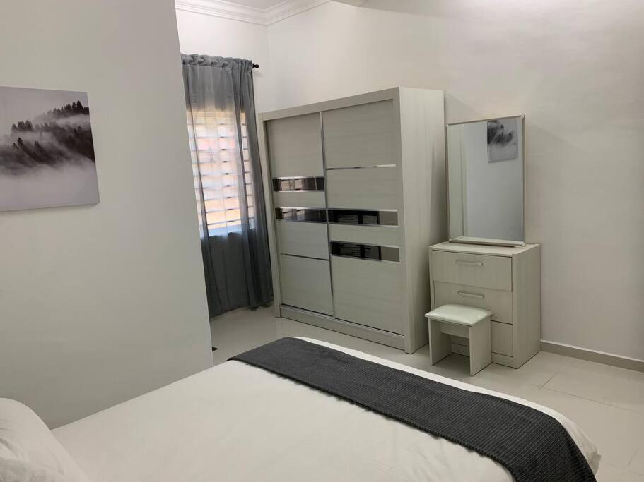 a white bedroom with a bed and a dresser at Impiana Homestay Jitra in Jitra