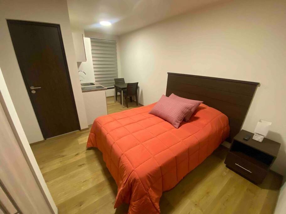 a bedroom with a bed with an orange comforter at Smart studio in Cochabamba