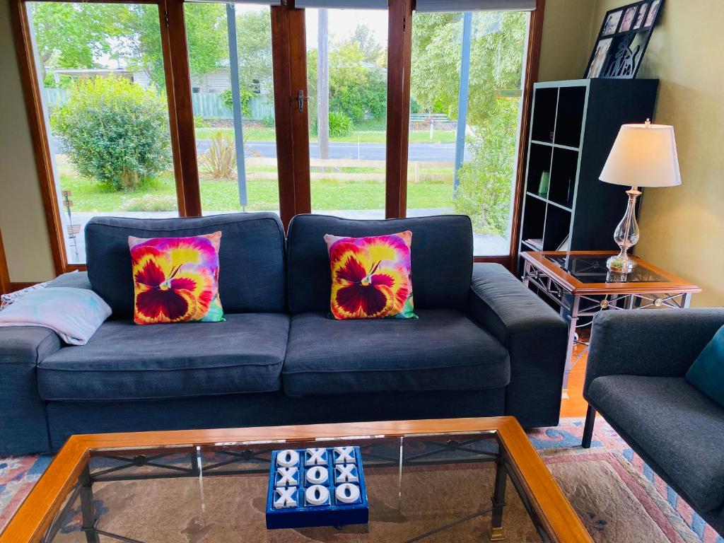 a living room with a blue couch and a glass table at Growse House Yarram 3BR in Yarram