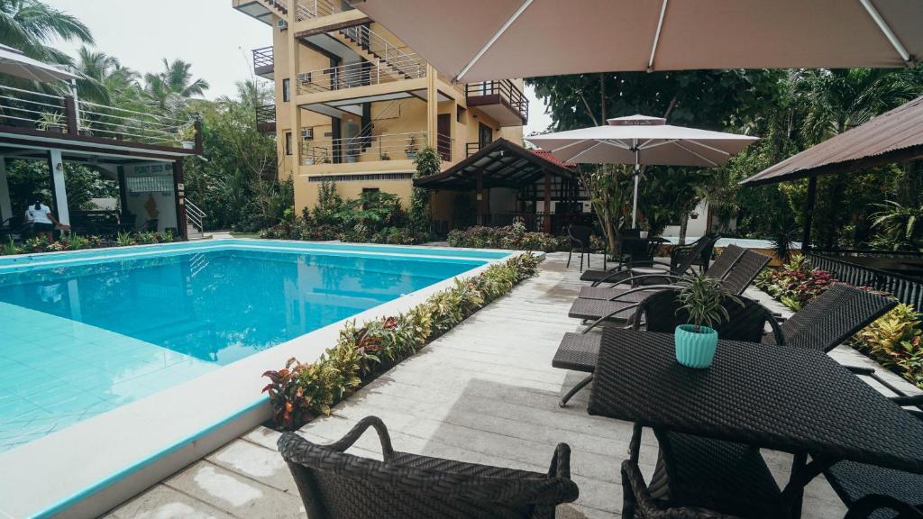 una piscina con sillas y una sombrilla junto a un edificio en Point 303 Resort en General Luna