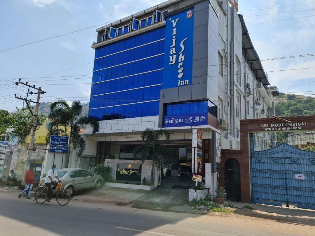 a building with a blue sign on the side of a street at Vijay Shree Inn in Vellore